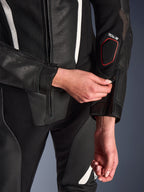Primer plano del traje de cuero de 2 piezas Alpinestars Stella GP-R7 en color negro, destacando el ajuste de la cremallera del antebrazo, con construcción de cuero perforado, detalles en blanco y el logotipo de compatibilidad con Tech-Air en la manga.