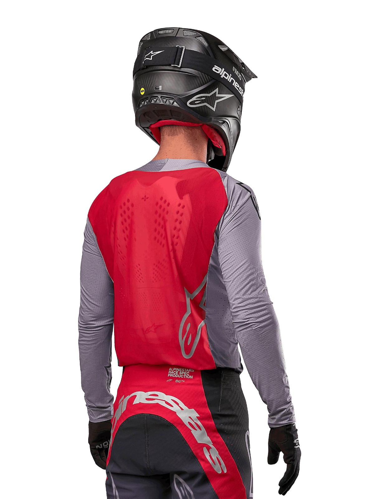 Piloto de motocross visto desde atrás vistiendo el Jersey Alpinestars 2024 Supertech Dade en color Iron Red Berry y gris, con un panel trasero de malla transpirable y detalles de logotipos plateados, combinado con un casco negro y pantalones de carreras a juego para un rendimiento profesional todoterreno.