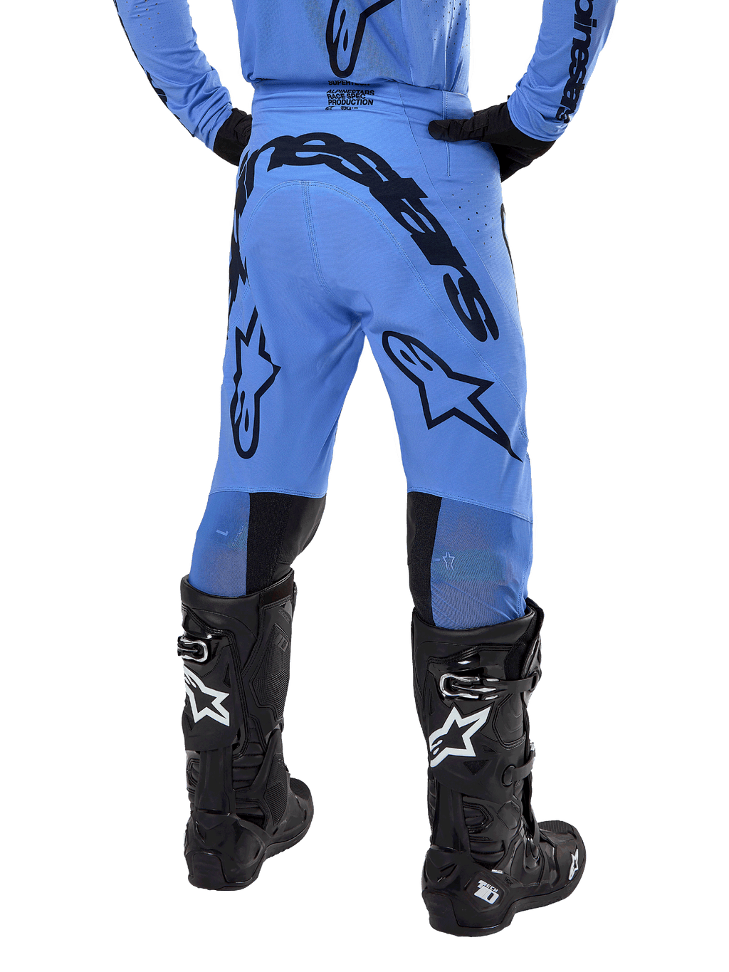 Alpinestars 2024 Supertech Dade Pants, pantalones de motocross, azul claro, vista trasera que muestra un gran logotipo negro en el asiento y las piernas, usados con botas Alpinestars Tech 10 negras, ajuste atlético de competición para un rendimiento profesional fuera de pista.
