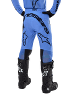 Alpinestars 2024 Supertech Dade Pants, pantalones de motocross, azul claro, vista trasera que muestra un gran logotipo negro en el asiento y las piernas, usados con botas Alpinestars Tech 10 negras, ajuste atlético de competición para un rendimiento profesional fuera de pista.