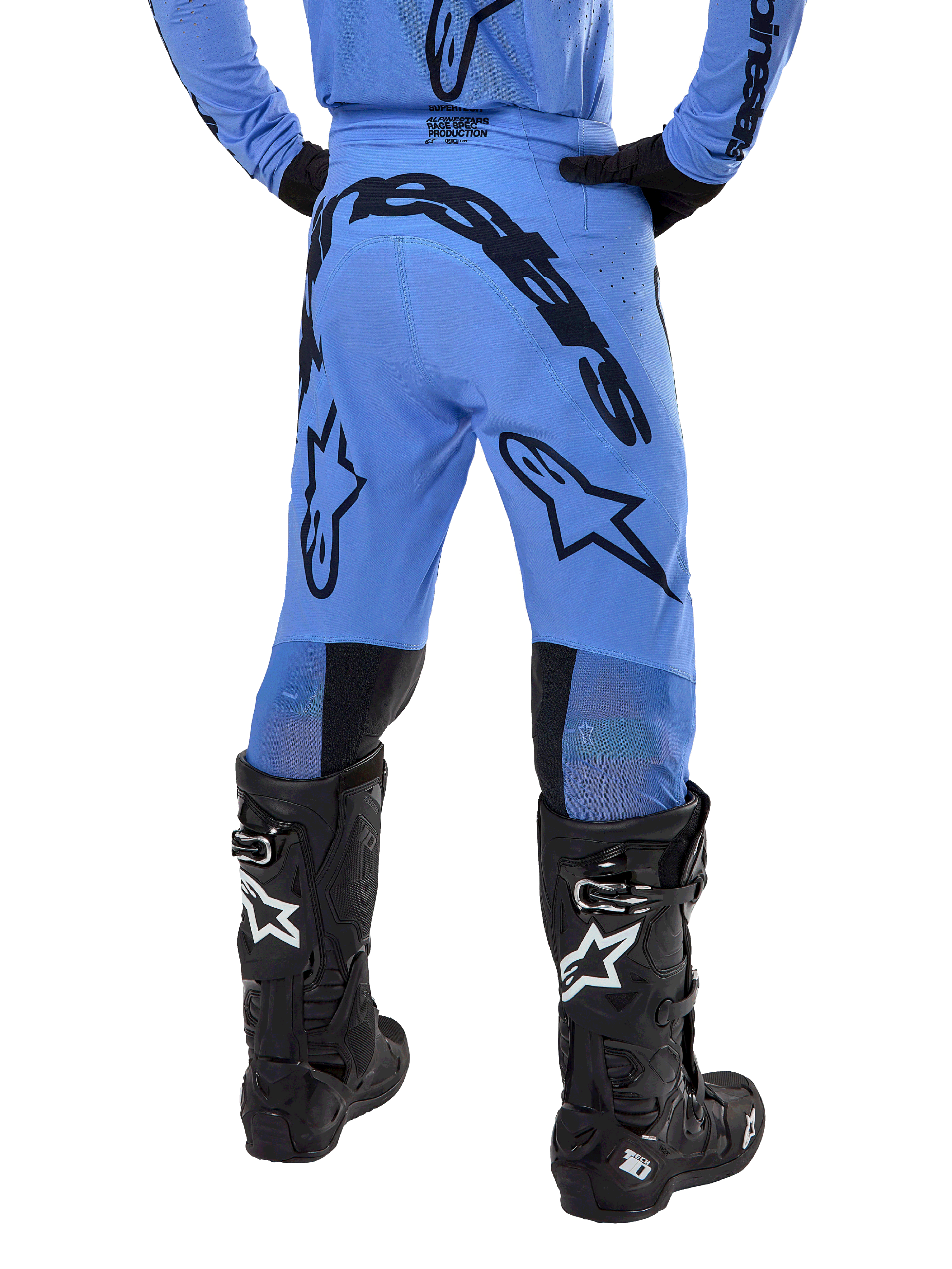 Alpinestars 2024 Supertech Dade Pants, pantalones de motocross, azul claro, vista trasera que muestra un gran logotipo negro en el asiento y las piernas, usados con botas Alpinestars Tech 10 negras, ajuste atlético de competición para un rendimiento profesional fuera de pista.