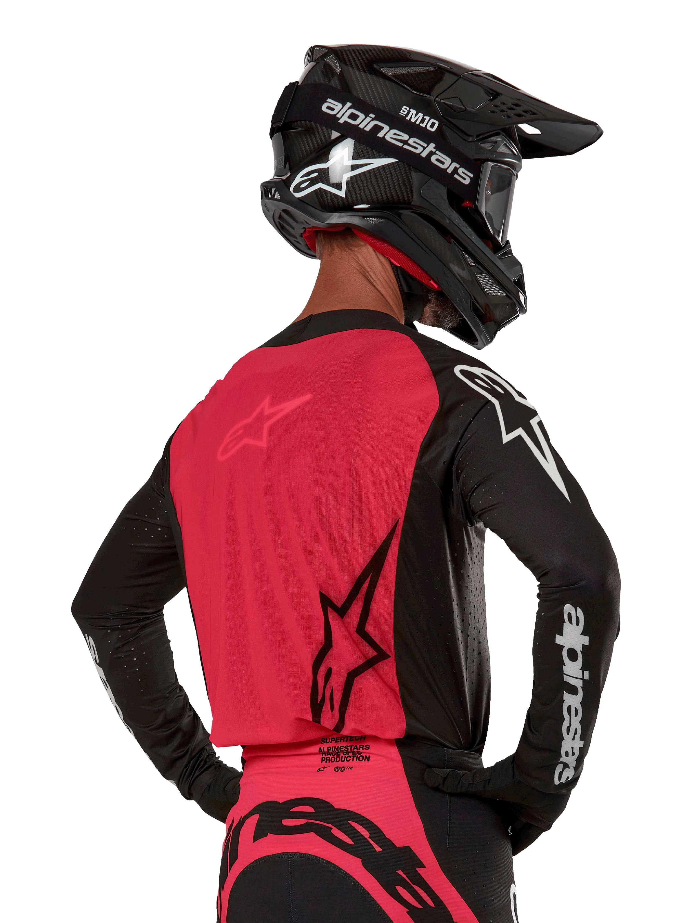 Alpinestars 2024 Supertech Ward Jersey, jersey de motocross, negro y rojo berry, vista posterior con panel de malla roja y mangas negras con logotipos blancos, usado con casco de fibra de carbono negro y guantes, ajuste de carrera atlético para conducción todoterreno