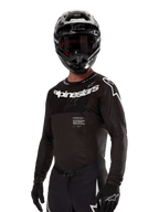 Alpinestars Supertech Ward Jersey 2024, jersey de motocross de manga larga, negro y blanco, equipo de alto rendimiento con marca Alpinestars destacada, usado con casco y guantes a juego, ajuste atlético para conducción todoterreno