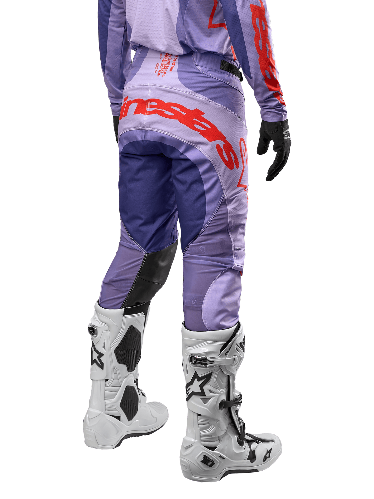 Alpinestars Techstar Ocuri Pants 2024, pantalones de motocross para hombre, color morado con detalles en naranja vibrante y azul oscuro, vista trasera mostrando el logo de Alpinestars, diseño ergonómico con paneles reforzados, usados con botas de motocross blancas.