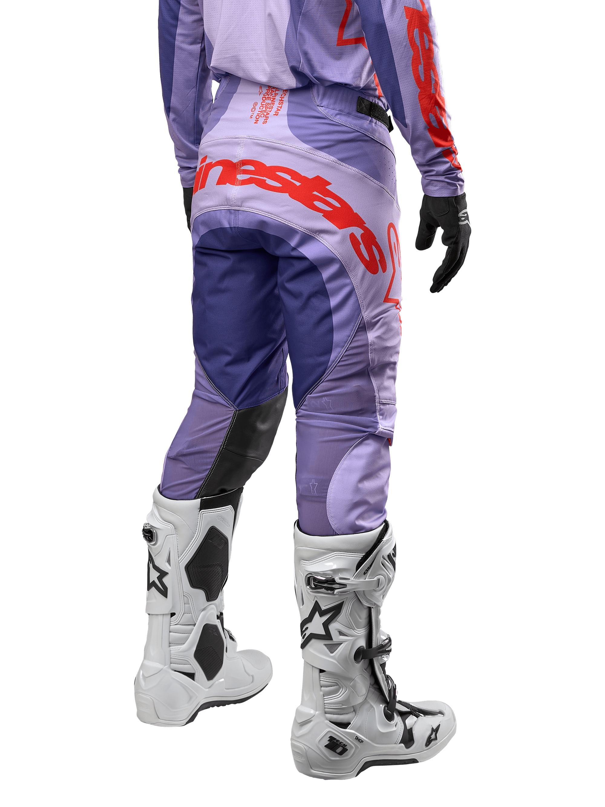 Alpinestars Techstar Ocuri Pants 2024, pantalones de motocross para hombre, color morado con detalles en naranja vibrante y azul oscuro, vista trasera mostrando el logo de Alpinestars, diseño ergonómico con paneles reforzados, usados con botas de motocross blancas.