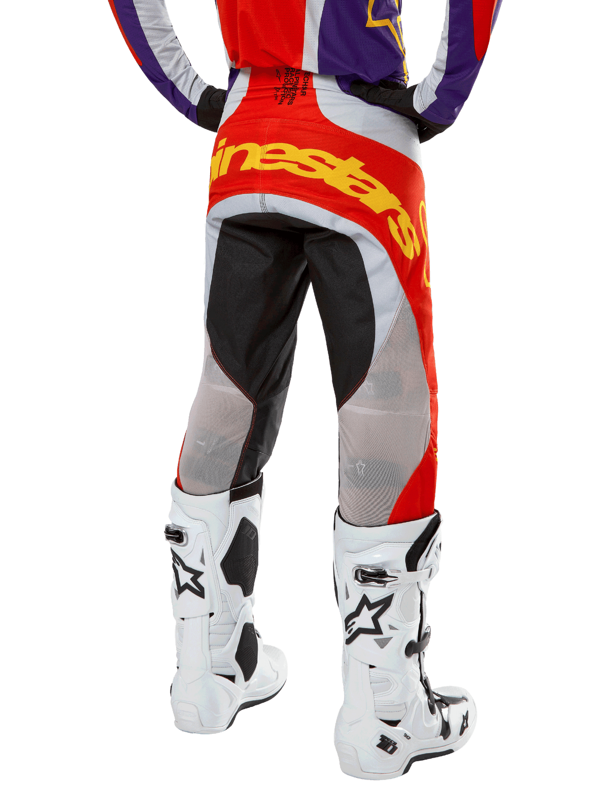 Alpinestars 2024 Techstar Ocuri Pants, pantalones de motocross, naranja intenso, púrpura y negro, vista posterior desde la cintura hacia abajo, marca amarilla llamativa en el asiento, paneles técnicos negros y grises, combinados con botas de motocross blancas