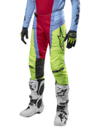 Alpinestars 2024 Techstar Ocuri Pants, pantalones de motocross en azul claro, rojo y amarillo neón, combinados con equipo a juego y botas blancas, con logotipos de Astars llamativos y un ajuste de competición.