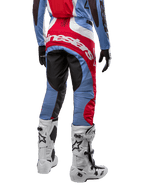 Pantalones Alpinestars Techstar Ocuri 2024, pantalones de motocross, azul claro, rojo Marte y blanco, vista trasera destacando el gran logotipo rojo de Alpinestars en el asiento, combinados con botas de carreras blancas y jersey a juego.