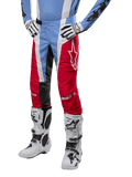 Alpinestars 2024 Techstar Ocuri Pants, pantalones de motocross, azul claro, rojo Marte y blanco, usados con jersey azul claro y botas blancas, con el logo de la estrella en el muslo y rodillas reforzadas, equipo completo para carreras todoterreno