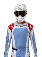 Alpinestars Techstar Ocuri Jersey 2024, jersey de motocross, azul claro, rojo Mars y blanco, vista frontal con ventilación cortada por láser y ajuste atlético, usado con casco blanco y gafas para un look profesional de competición off-road