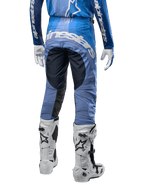 Alpinestars Techstar Pneuma Pants 2024, pantalones de motocross, azul marino y azul claro, vista trasera con logotipo blanco llamativo en el asiento y paneles negros reforzados, combinados con botas de motocross Tech 10 blancas.