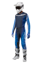Alpinestars Techstar Pneuma Pants 2024, pantalones de motocross en azul marino y azul claro, conjunto completo de carreras con jersey a juego, casco blanco con gafas, guantes azules y blancos, y botas blancas, equipamiento profesional para off-road