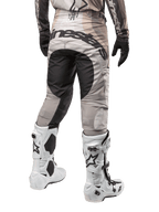 Pantalones Alpinestars Techstar Pneuma 2024, pantalones de motocross, color arena oscura y gris, vista trasera desde la cintura para abajo, logotipo negro de Alpinestars en el asiento, usados con botas de motocross blancas y negras y guantes negros, diseño duradero para competición off-road