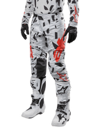 Alpinestars Techstar Rantera 2024, pantalones de motocross, camuflaje gris con patrón abstracto negro y rojo, usados con jersey a juego, guantes negros y botas de motocross blancas, diseñados para carreras todoterreno de alto rendimiento