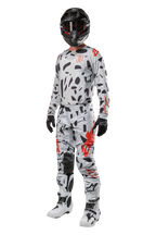 Alpinestars 2024 Techstar Rantera Pants, pantalones de motocross, gris camuflaje (Haze Gray Camo), combinados con jersey a juego, casco negro y botas blancas y negras, con patrones abstractos negros y detalles rojos, equipo completo de carreras todoterreno