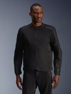 Modelo masculino con la chaqueta Alpinestars C-1 Air en negro, chaqueta de moto contemporánea con amplios paneles de malla técnica y cremallera frontal completa, combinada con pantalones de montar negros a juego, estética de estilo de vida urbano y desplazamientos