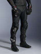 Alpinestars Missile V3 Leather Pants, pantalones negros de carreras para moto, usados con guantes GP Pro a juego y botas técnicas de carreras, construcción de cuero premium con deslizadores de rodilla con logo blanco, estética profesional para pista y carretera