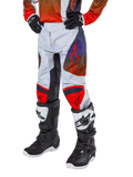 Alpinestars Pantalones Racer Hoen Juveniles 2024, pantalones de motocross, gris claro con detalles en naranja intenso y negro, con logotipos de estrellas rojas en los muslos y paneles rojos en las rodillas, usados con botas negras y blancas, diseño duradero para carreras todoterreno