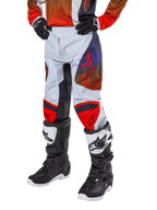 Alpinestars Pantalones Racer Hoen Juveniles 2024, pantalones de motocross, gris claro con detalles en naranja intenso y negro, con logotipos de estrellas rojas en los muslos y paneles rojos en las rodillas, usados con botas negras y blancas, diseño duradero para carreras todoterreno