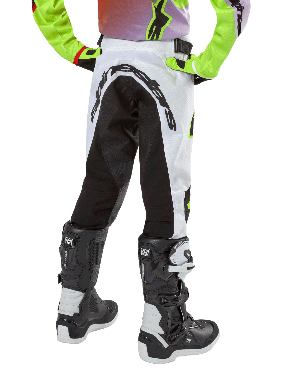 Alpinestars Youth 2024 Racer Lucent Pants, pantalones de motocross para jóvenes, blancos y negros con acentos neón, vista posterior que muestra el panel elástico trasero y el logo de Alpinestars, combinados con botas Alpinestars Tech Series blancas y negras