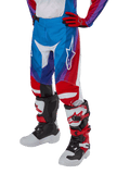 Alpinestars Youth 2024 Racer Pneuma Pants, pantalones de motocross juveniles, en azul, rojo y blanco, combinados con guantes y botas a juego, con el logotipo de la estrella blanca en el muslo, diseño deportivo para conducción fuera de carretera