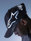 Alpinestars RSRV Resurgence Hat, gorra negra con logo blanco prominente, diseño urbano premium, visera curva, construcción de tela