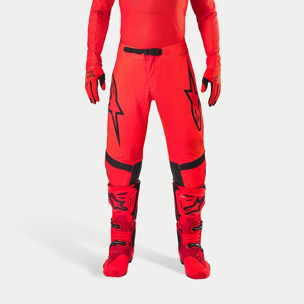 Alpinestars Supertech Ember LE Pants, pantalones de motocross, rojo flúor y rojo brillante con detalles en negro, con logotipos de estrellas negros en los muslos, hebilla de cintura y paneles en las rodillas negros, combinados con botas y guantes rojos a juego para un conjunto de competición coordinado.