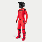 Piloto de motocross con equipo completo de competición, jersey y pantalones Supertech Ember LE en rojo flúor y negro, casco negro con gafas, botas y guantes a juego en rojo y negro, conjunto profesional coordinado para carreras todoterreno