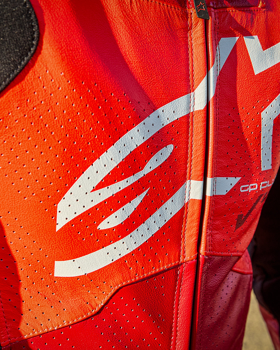 Alpinestars GP Plus V4 Sprint Leather Suit in Red Fluo, close-up of perforated racing leather and white logo.